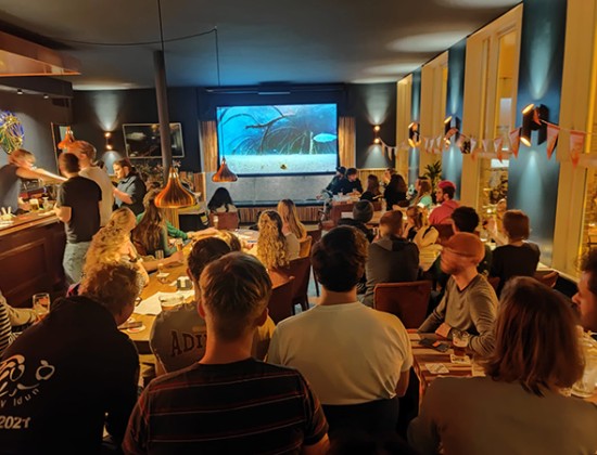 Mensen in cafe de Burcht kijken naar het grote scherm